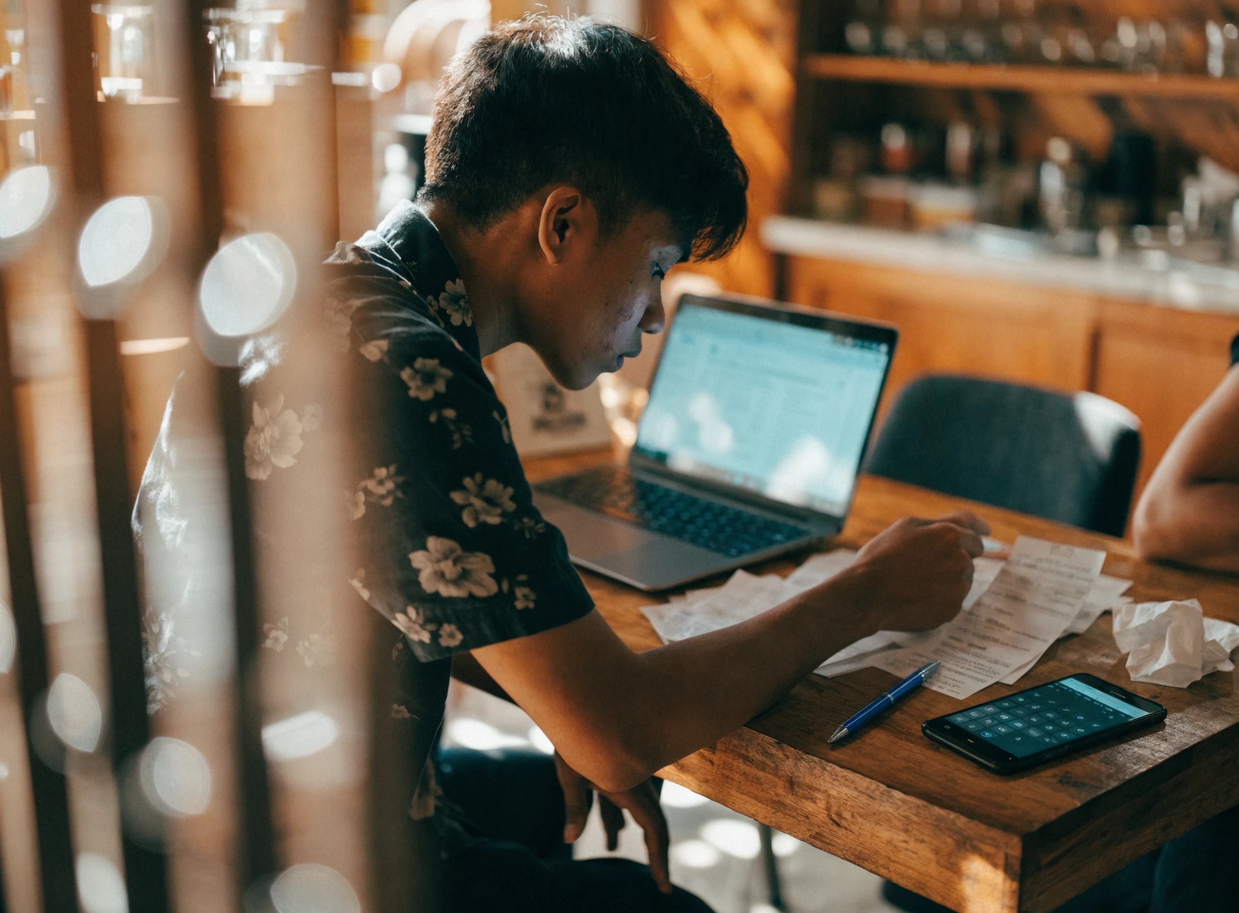Pemilik perniagaan menyemak resit di sebelah laptop di atas meja