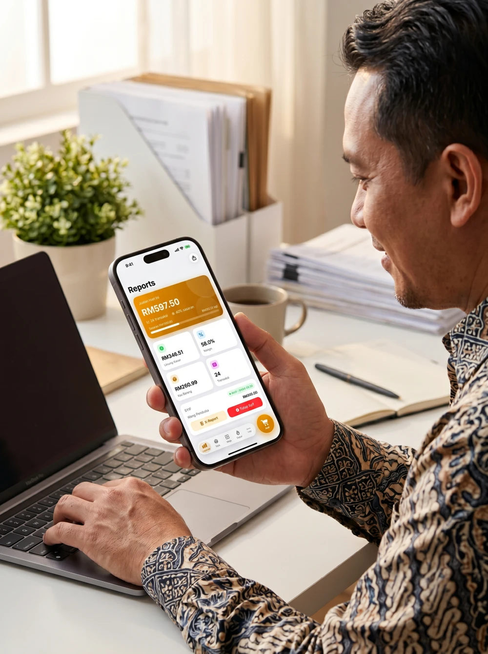 Skrin Laporan Pitis sebenar pada iPhone dipegang pemilik perniagaan di meja