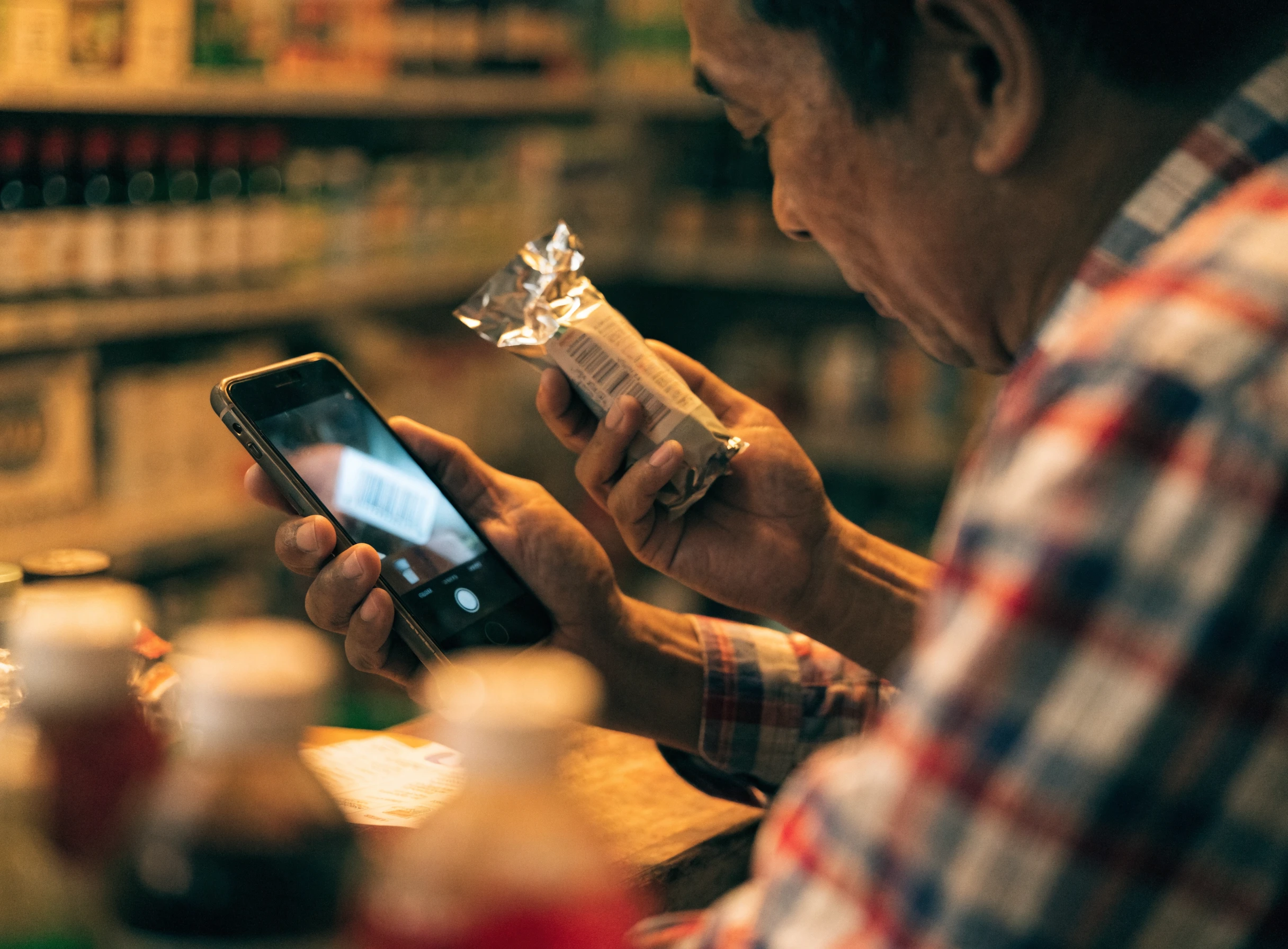 Peniaga mengimbas barcode produk dengan kamera telefon di kaunter