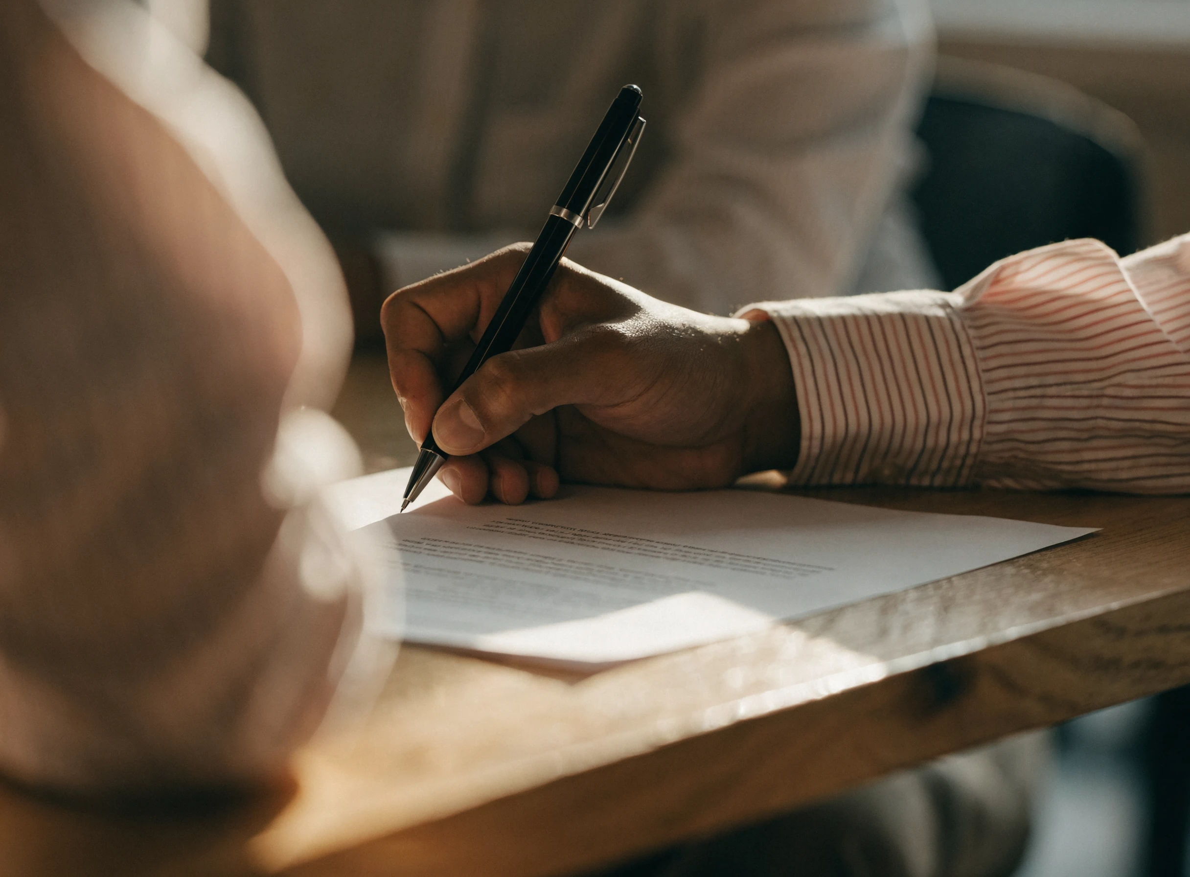 Seseorang menandatangani kontrak dengan pen di atas meja