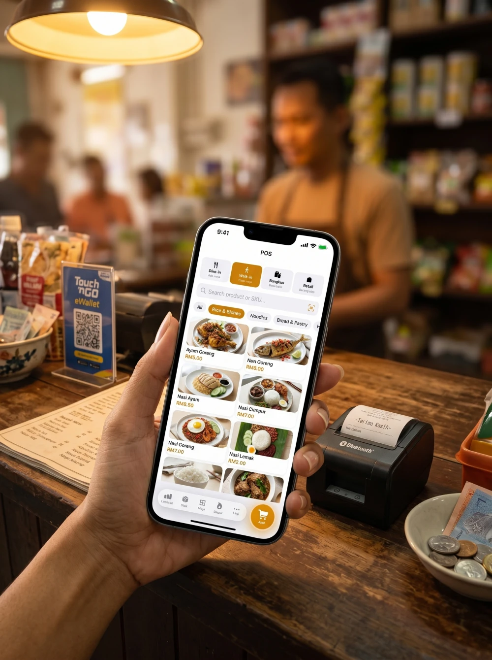 Skrin POS Pitis sebenar pada iPhone di sebelah printer thermal Bluetooth