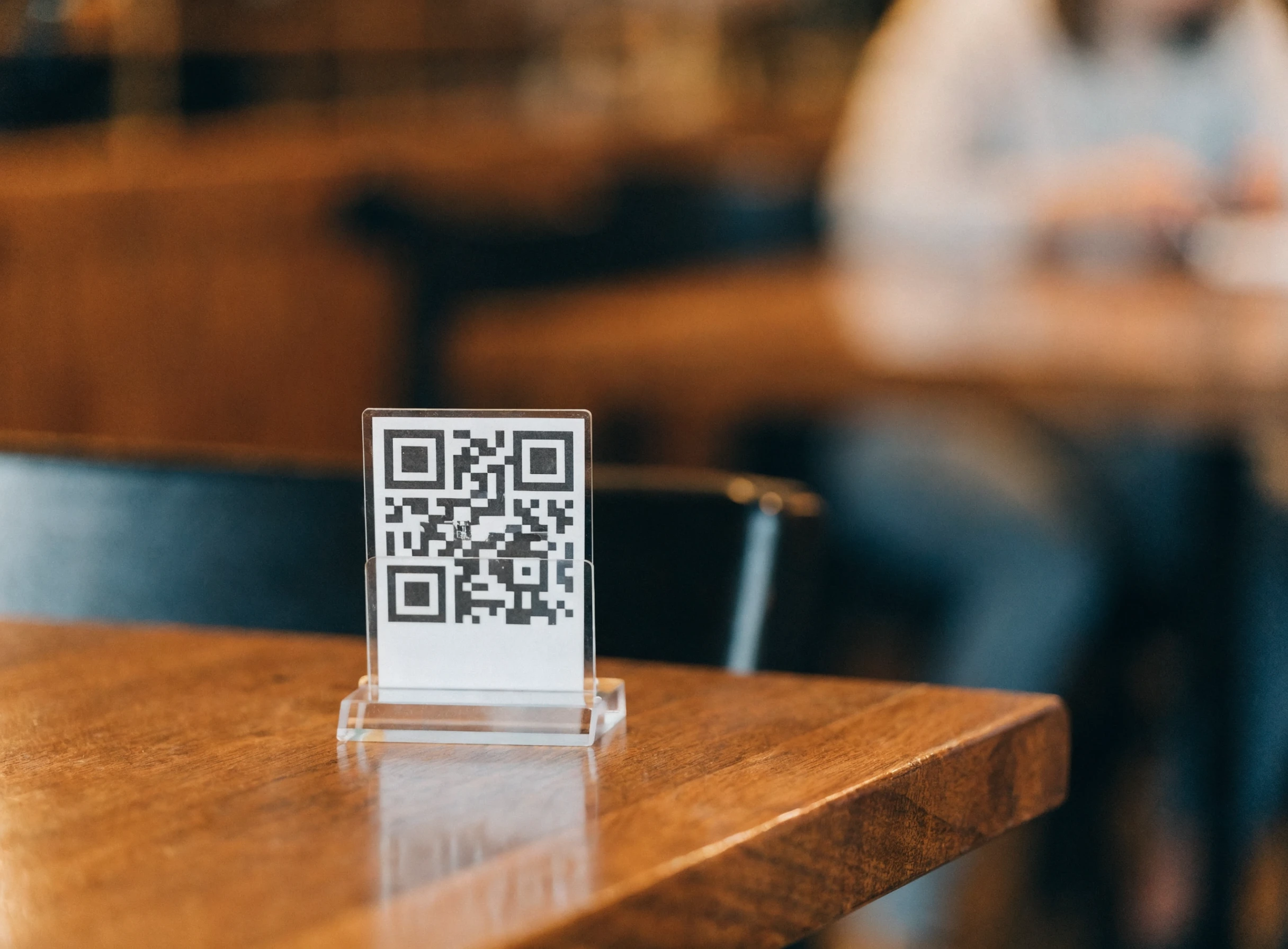 Dudukan kod QR kecil di atas meja restoran
