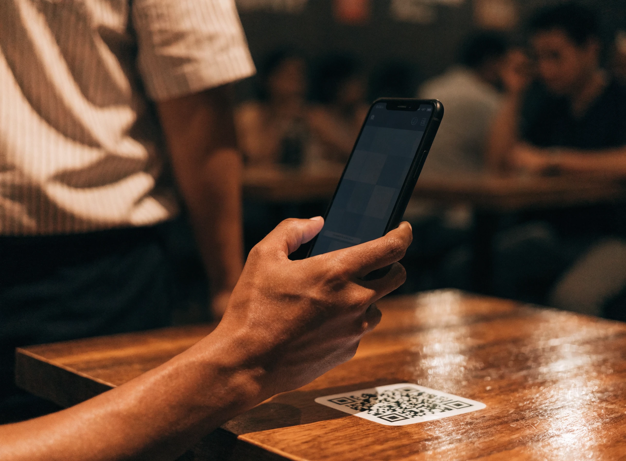 Pelanggan mengimbas kod QR meja dengan telefon, menu terpapar di skrin